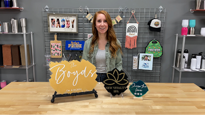 Woman standing behind a table displaying personalized signs