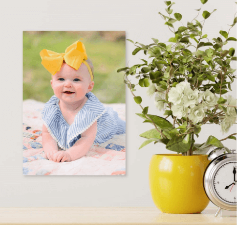 Picture hung on the wall of a baby with a large yellow bow on their head